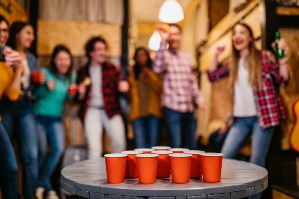 0 Young people playing beer pong in hostel