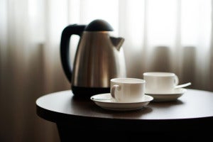 0 white tea cup coffee cup on the table by a sofa couch in hotel room kettle