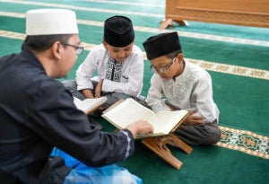 Teaching Muslim Kid To Read Quran Teacher Teaching Muslim Kid How To Read Holy Quran Mosque 180247679 640X438 1